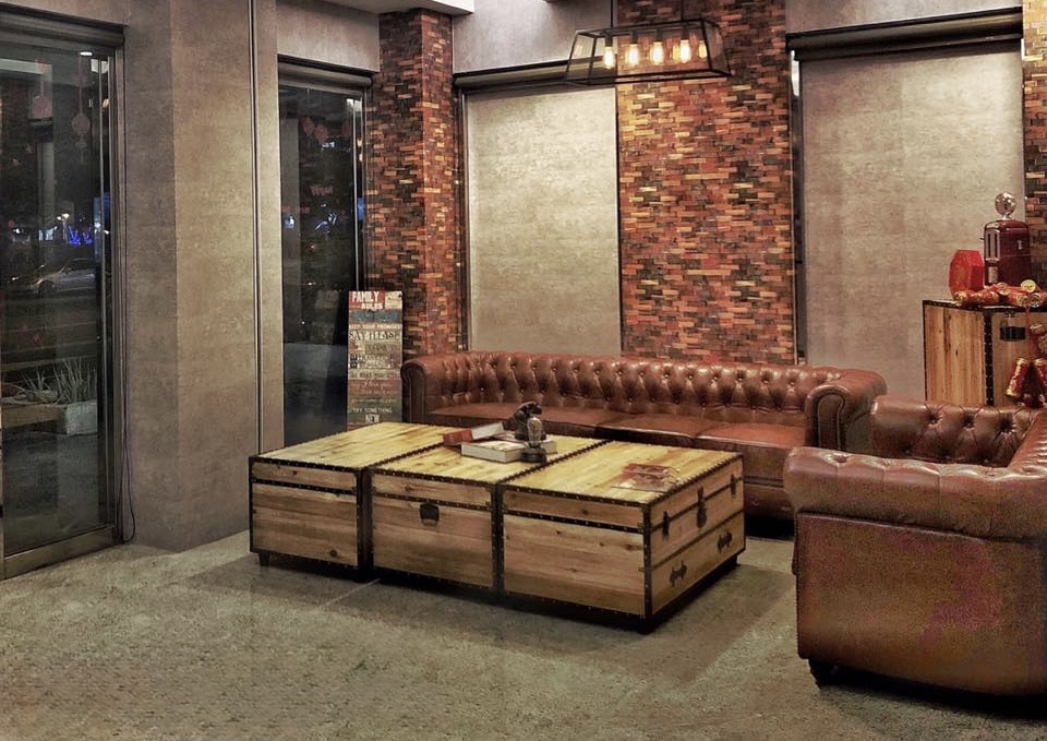 Chesterfield Style A 英式拉扣皮沙發於旅店大廳接待區，搭配紅磚牆營造復古氛圍