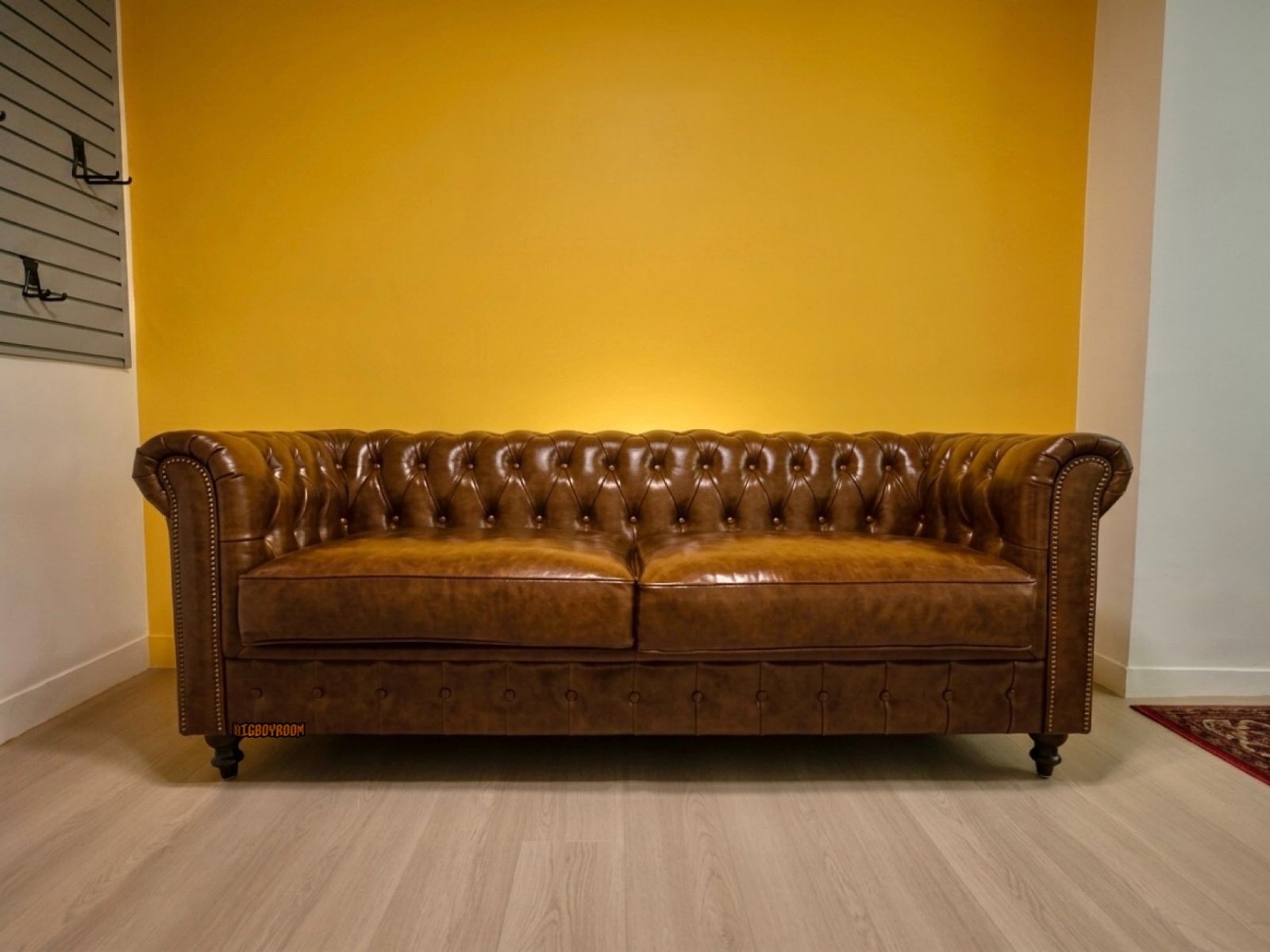 台北大安區私宅客廳裝潢，經典焦糖棕色 Chesterfield Style A 三人座英式沙發，搭配黃色背景牆展現頂級油蠟皮工藝質感